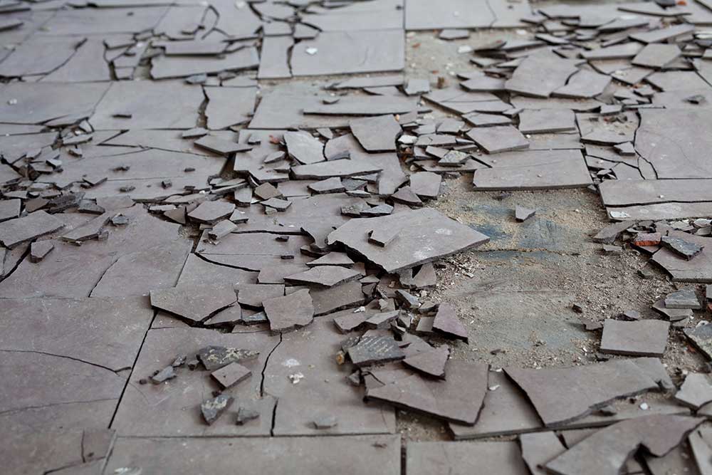 Broken gray pavement tiles scattered across a cracked sidewalk.