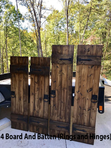 Rustic wooden board-and-batten fence panels with rings and hinges outdoors against trees.