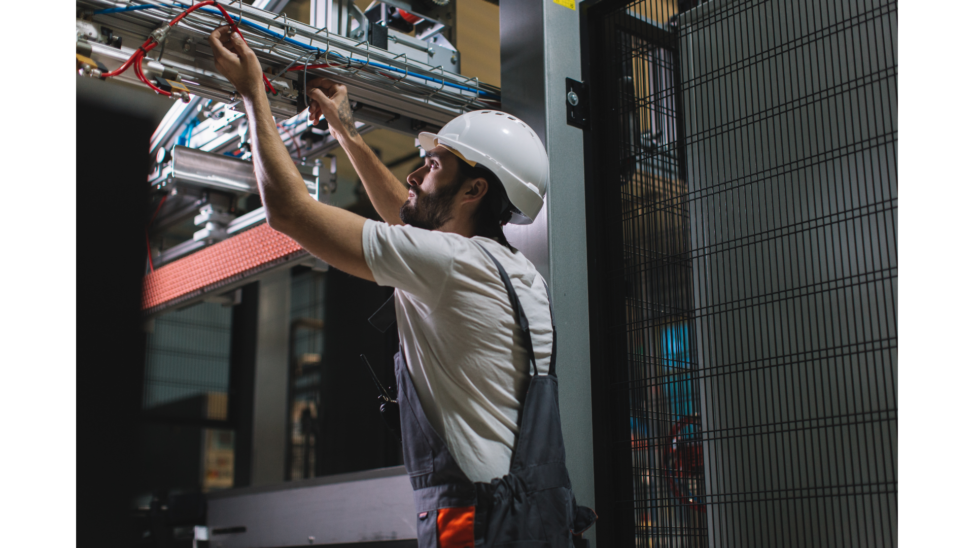 A man in a hard hat is working on a machine in a factory.