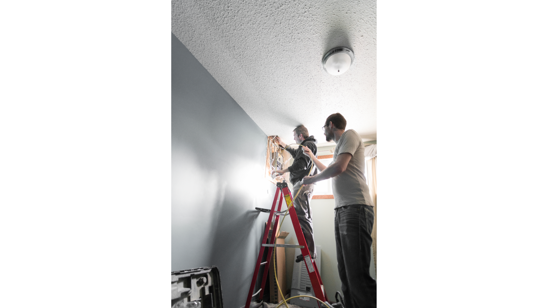 A group of men are standing on a ladder in a room.