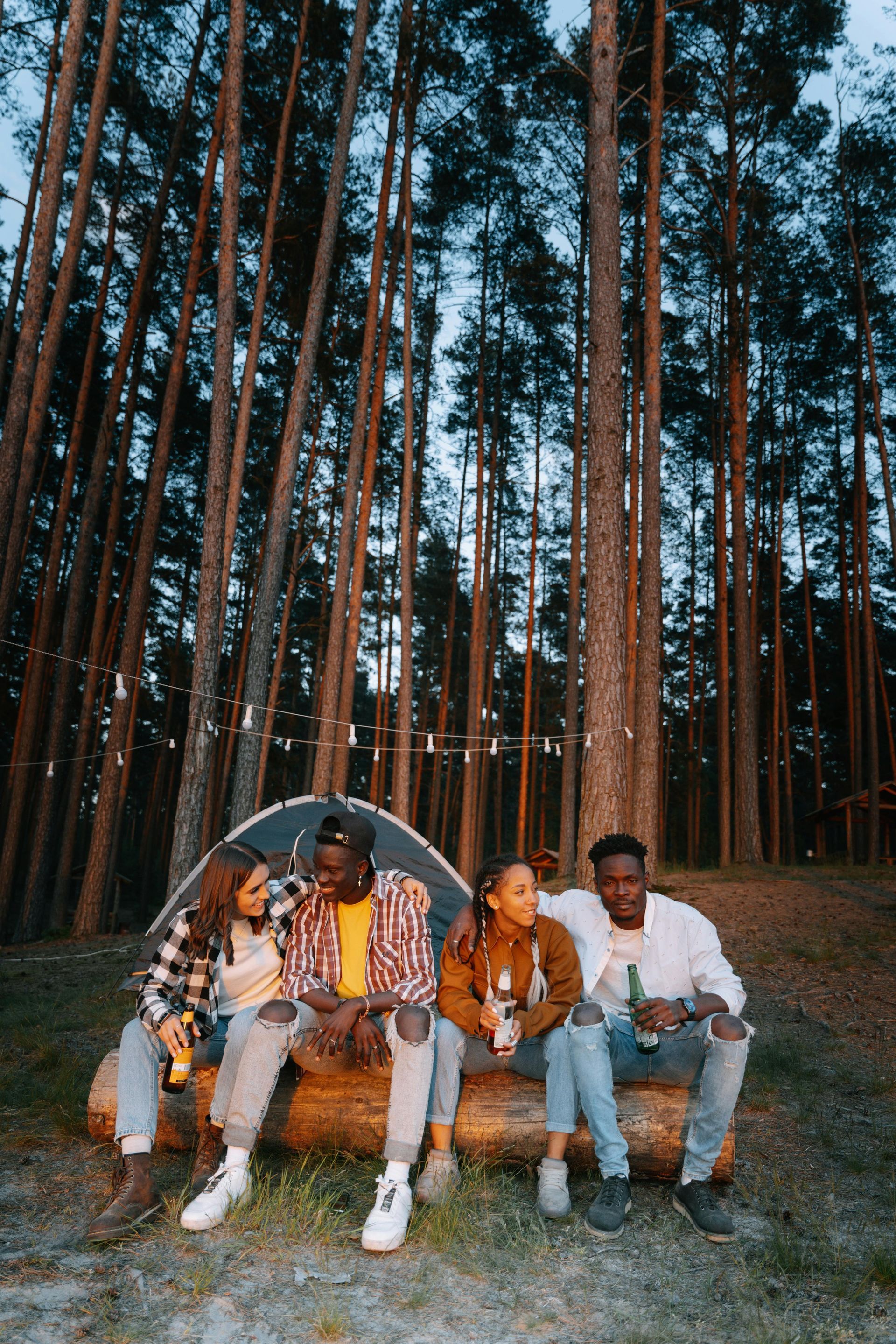 A group of people are sitting on a log in the woods.