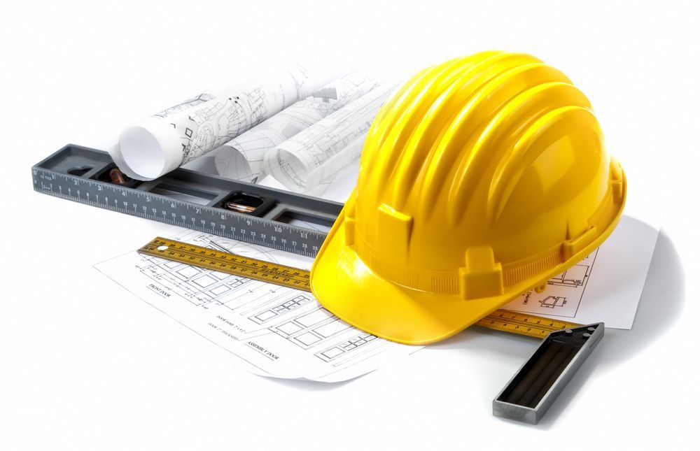 A yellow hard hat is sitting on top of a stack of blueprints.