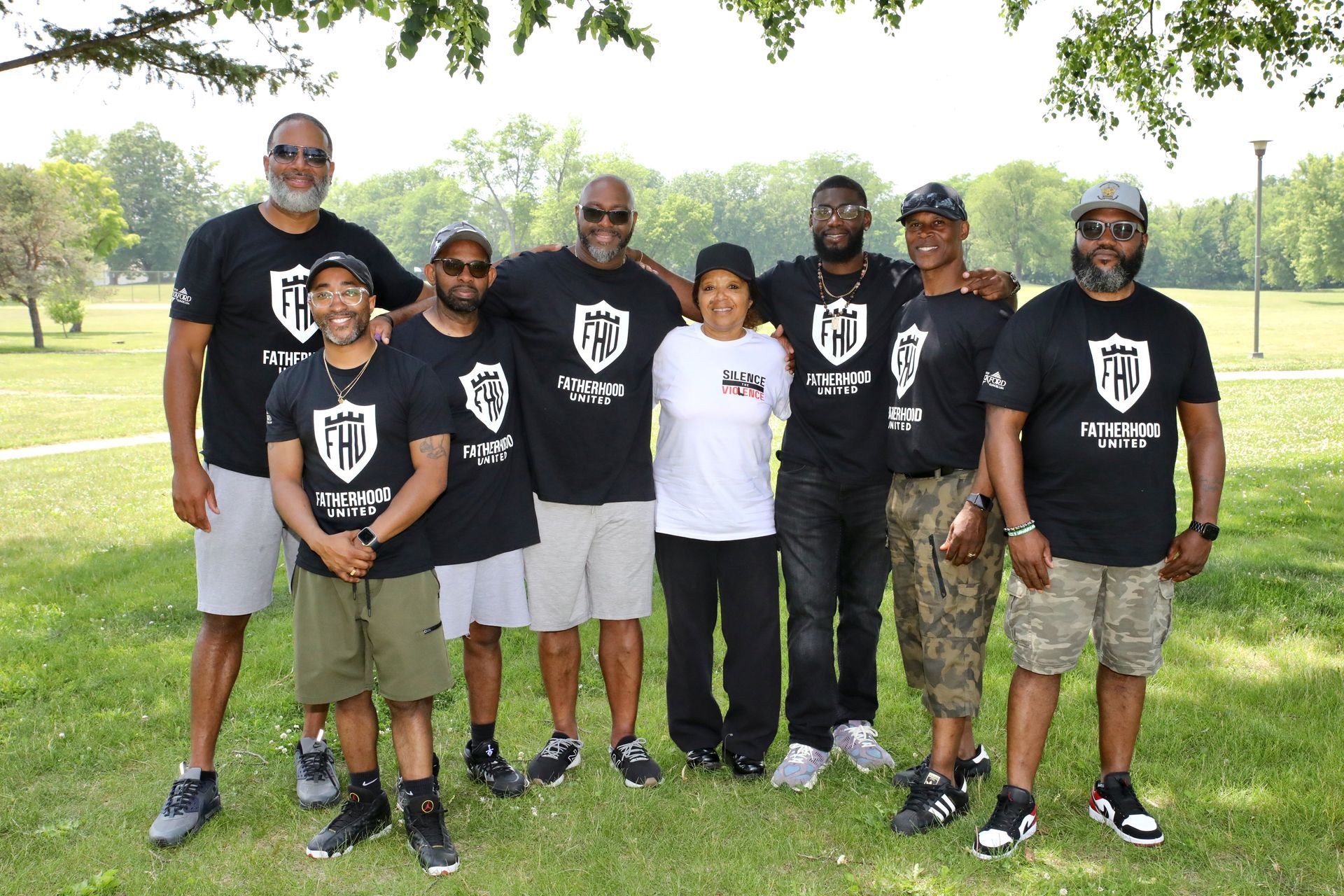 Group of people wearing matching t-shirts, posing in a park.