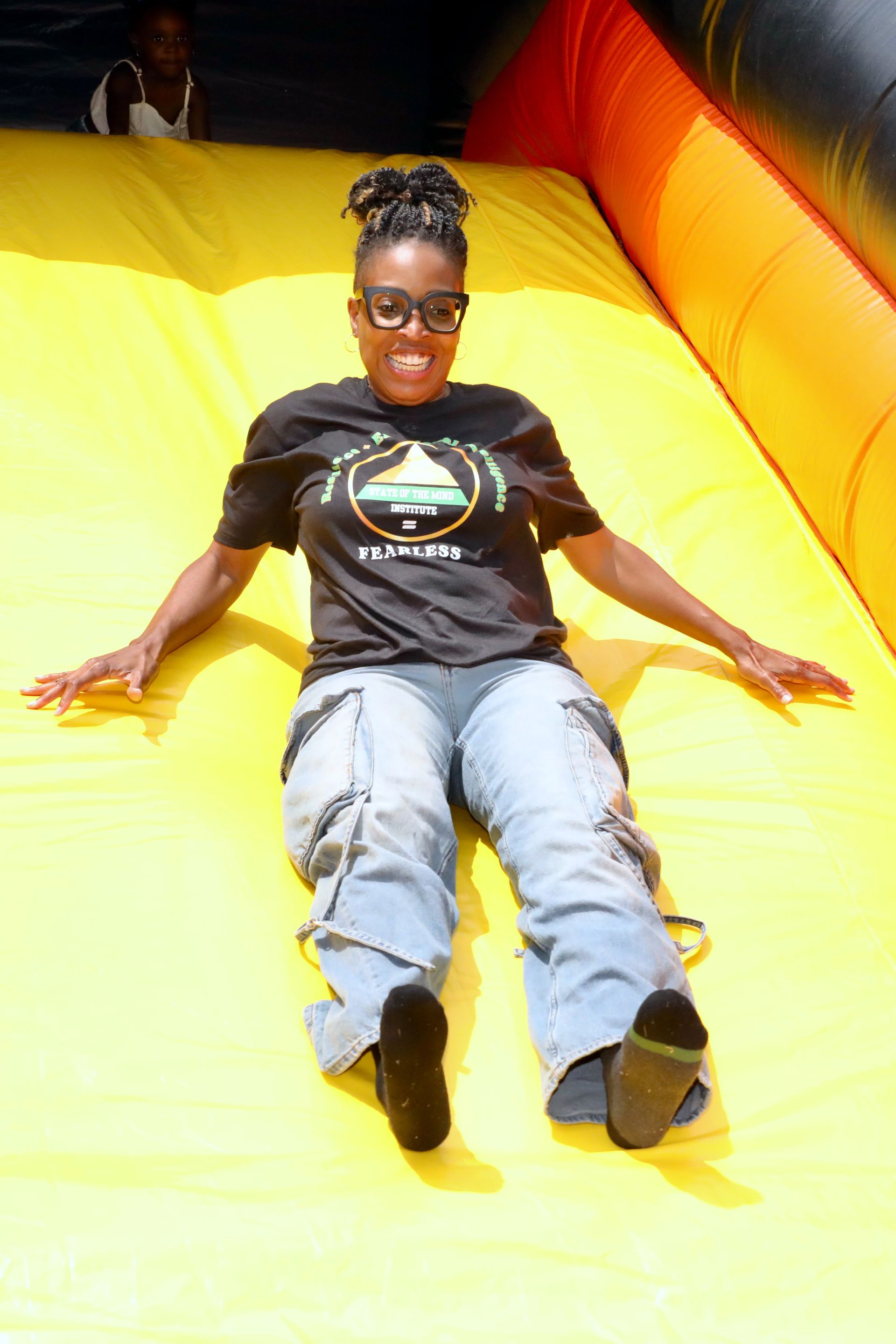 Woman sliding down a yellow inflatable slide, smiling.