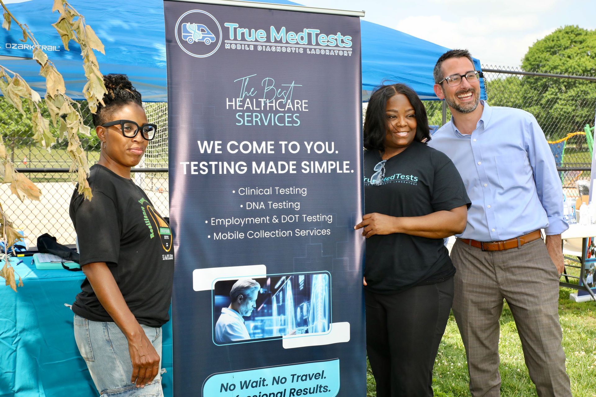 Three people stand near a banner for 
