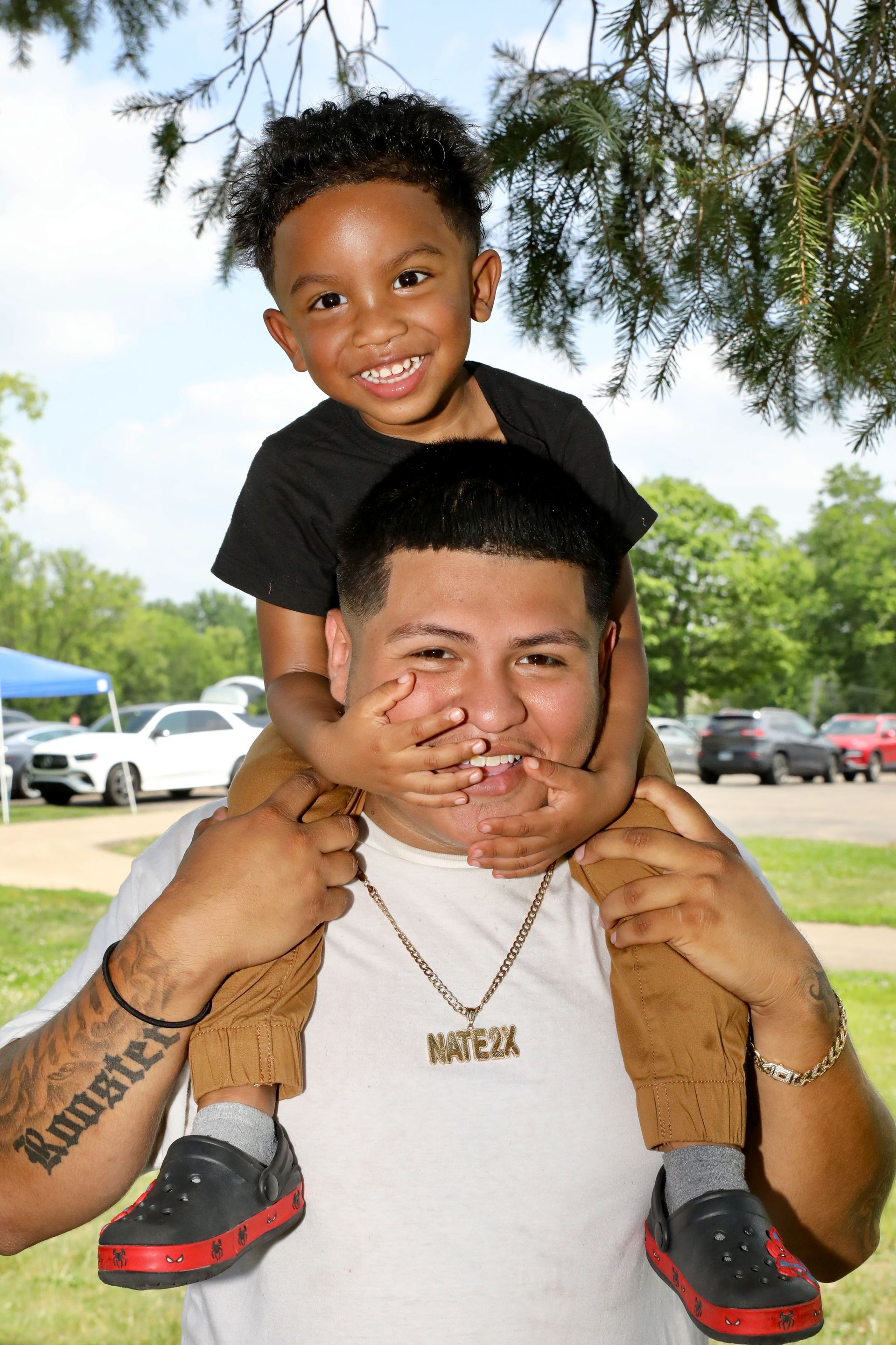 Child on shoulders of man smiling outdoors.