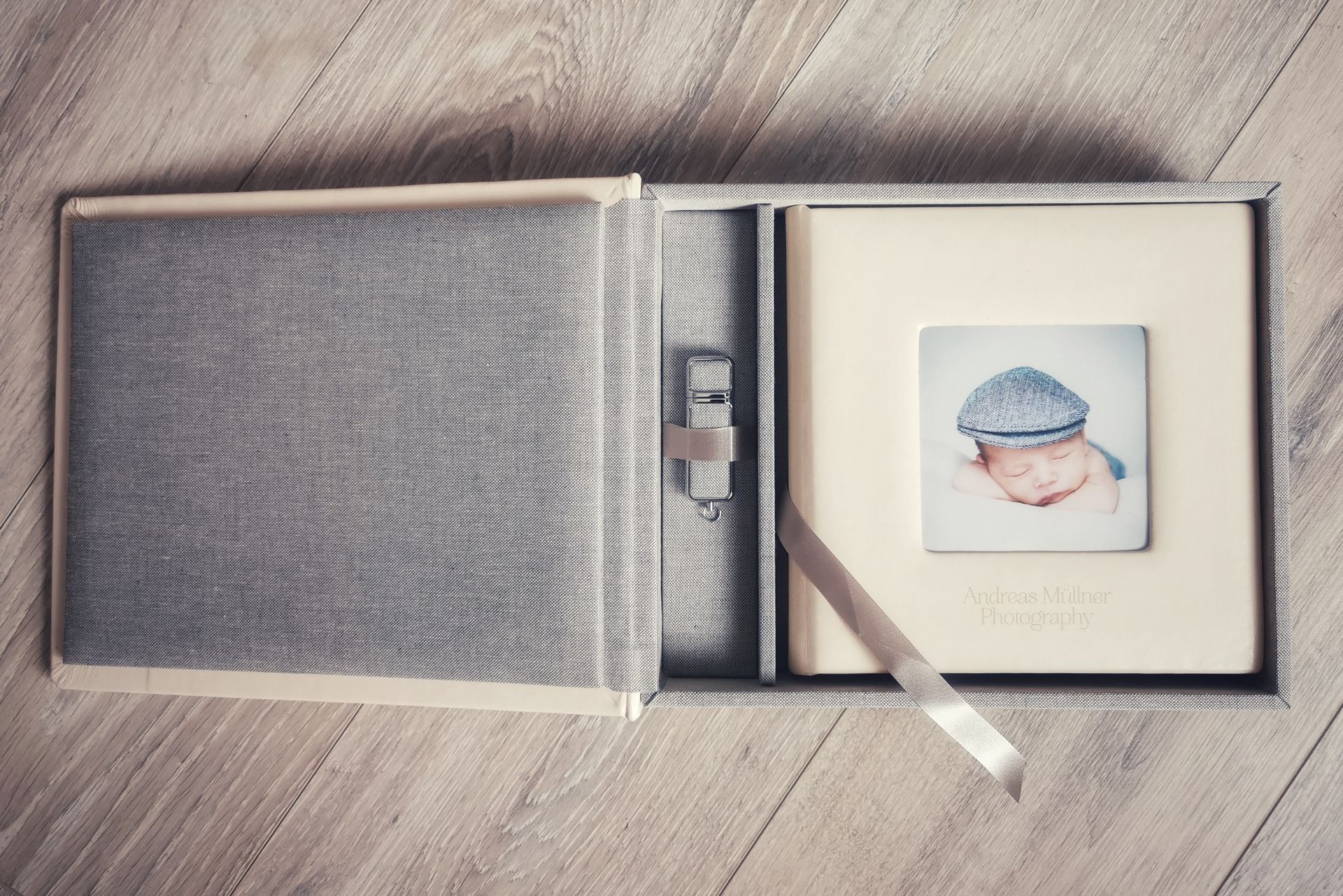 Aufgeschlagenes Fotoalbum mit einem kleinen Babyporträt und einem Lesezeichen aus Schleife auf einer Holzoberfläche