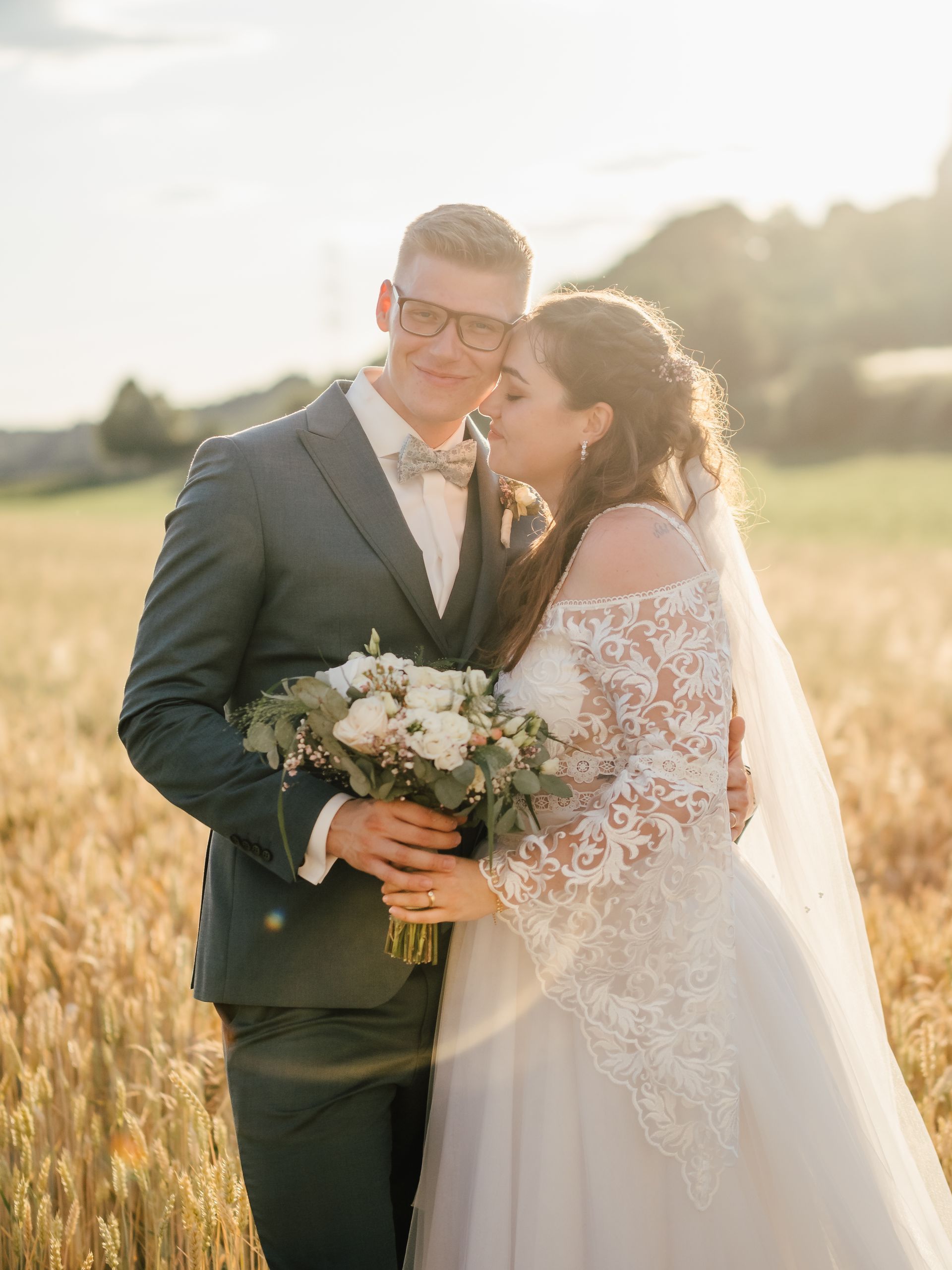 Ein Paar in Hochzeitskleidung umarmt sich auf einem sonnenbeschienenen Feld