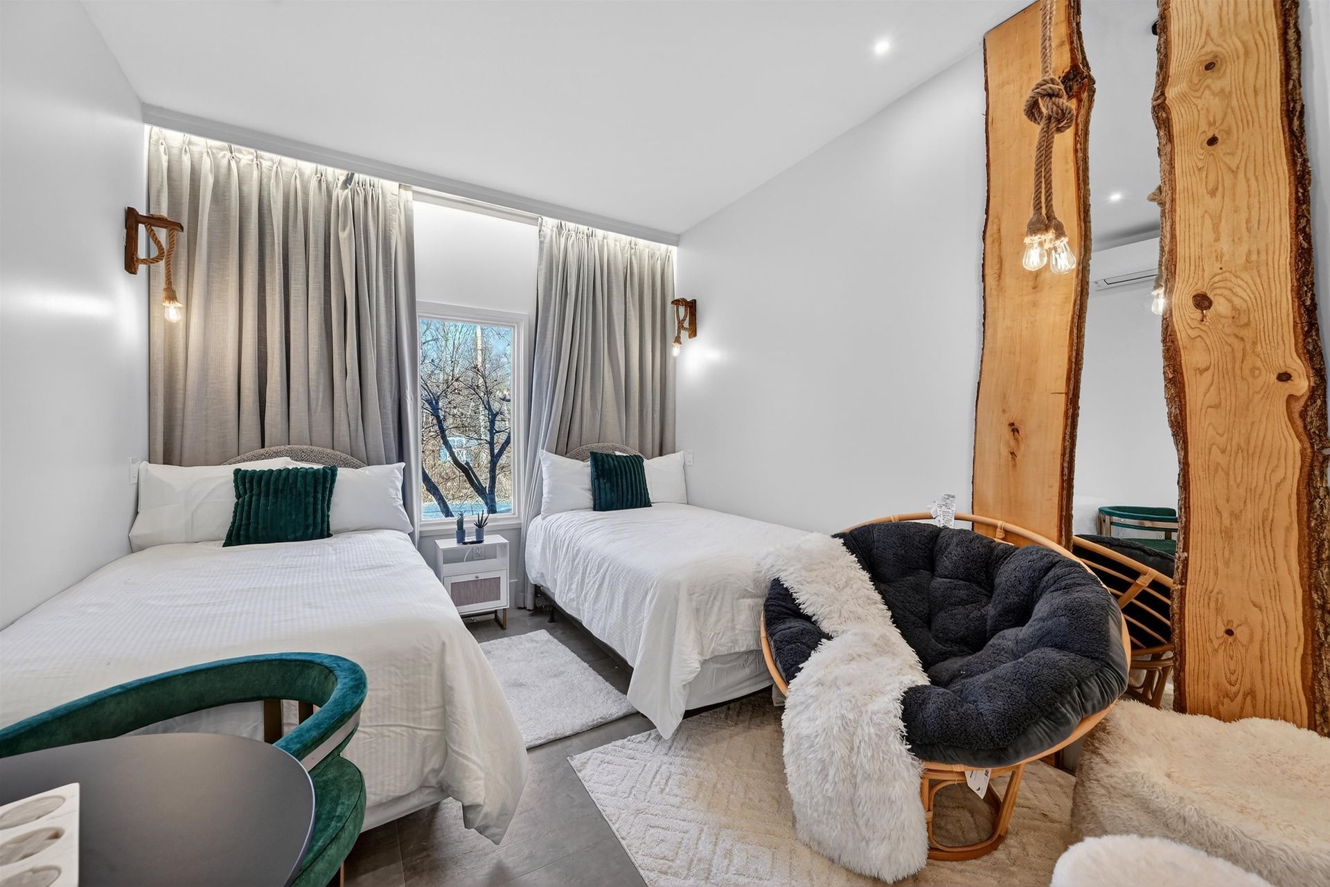 Bright twin bedroom with white bedding, gray curtains, teal chair, and rustic wood mirror frame