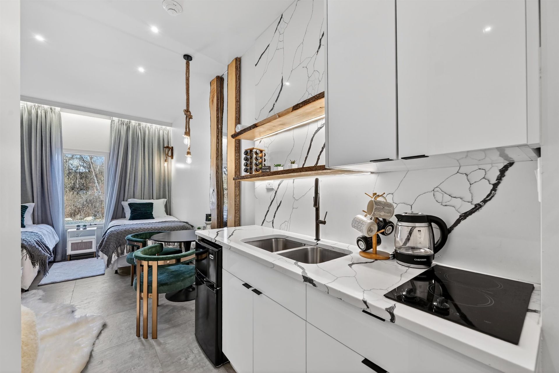 Modern kitchen with white cabinets, marble backsplash, and a small dining nook by the window