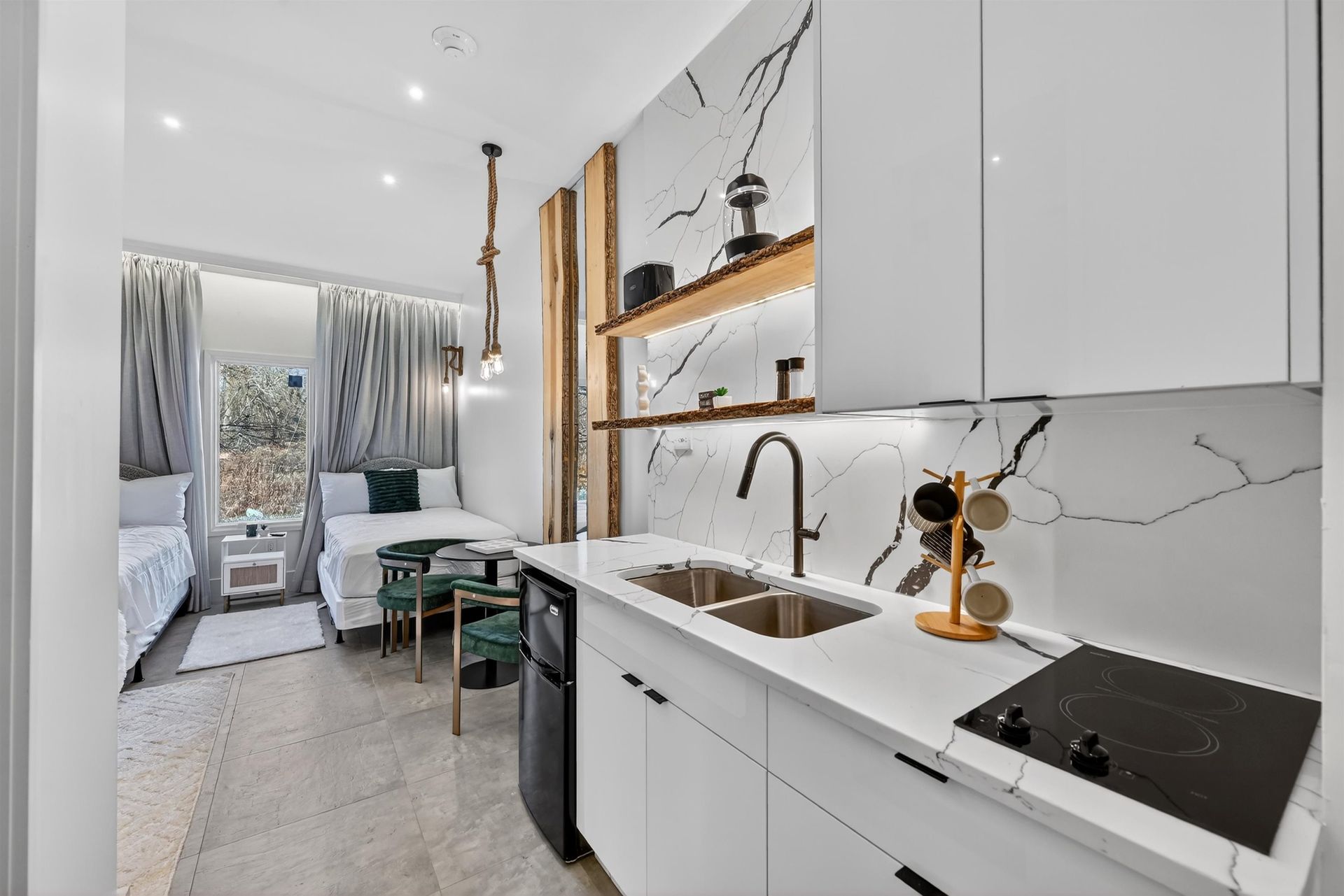 Bright modern kitchenette with white cabinets, wood shelves, and a small dining nook by a window