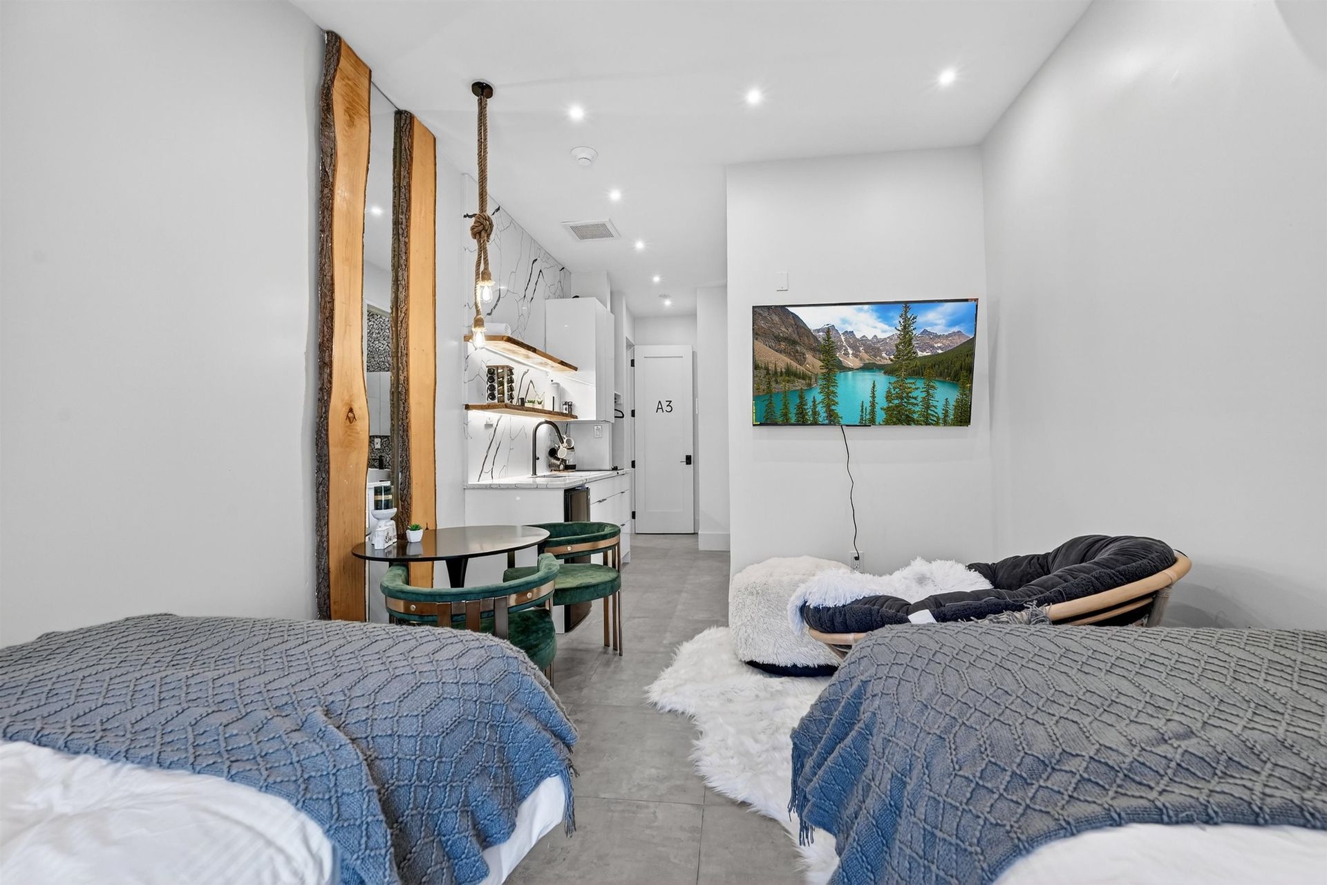 Bright modern bedroom with two beds, a desk, white shelves, and a TV on the wall