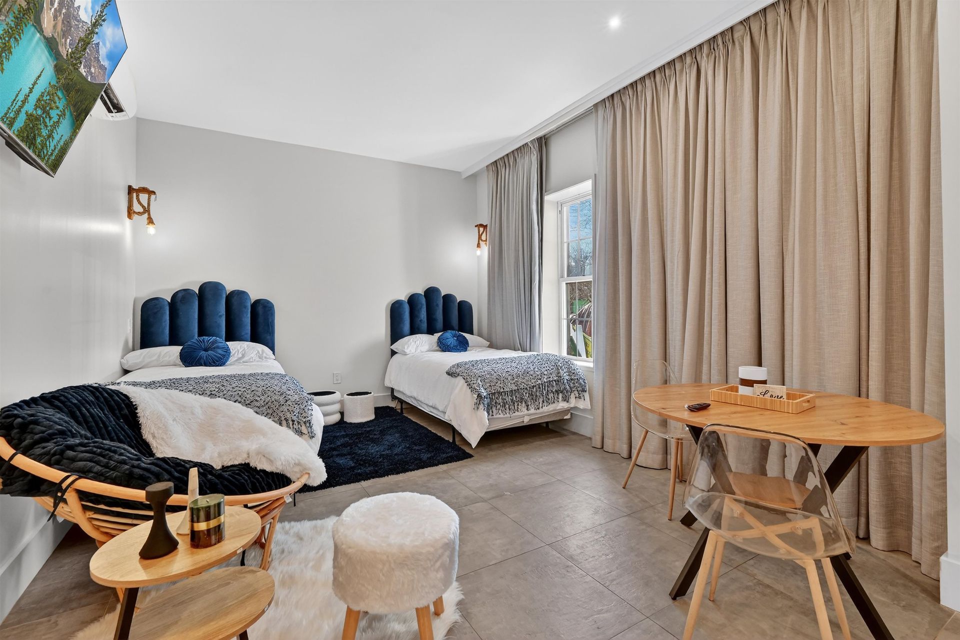 Bright bedroom with two beds, curtains, and a small table by a window