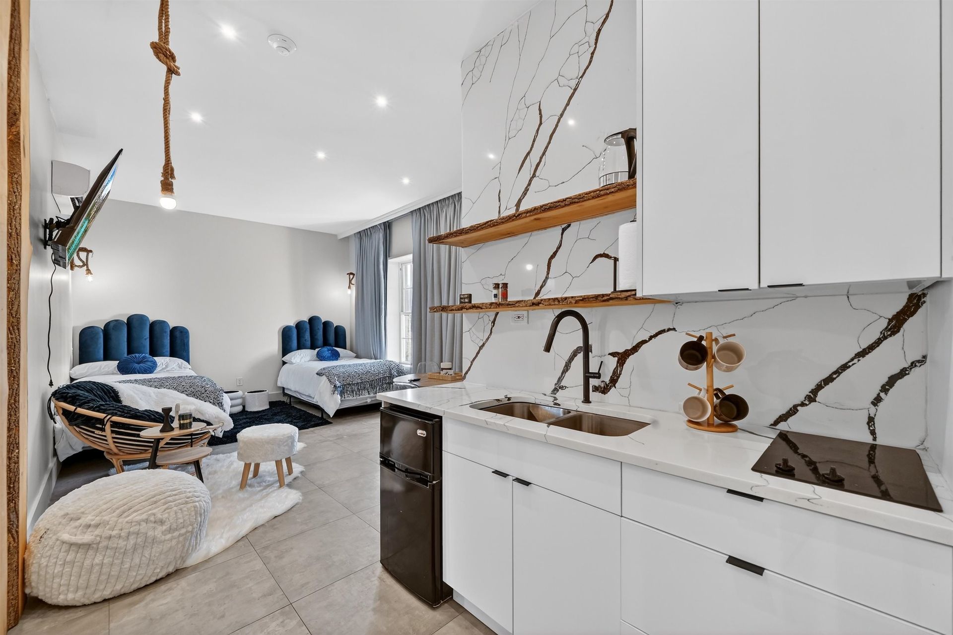 Bright modern kitchen opening to a cozy bedroom with blue accents and a tufted chair