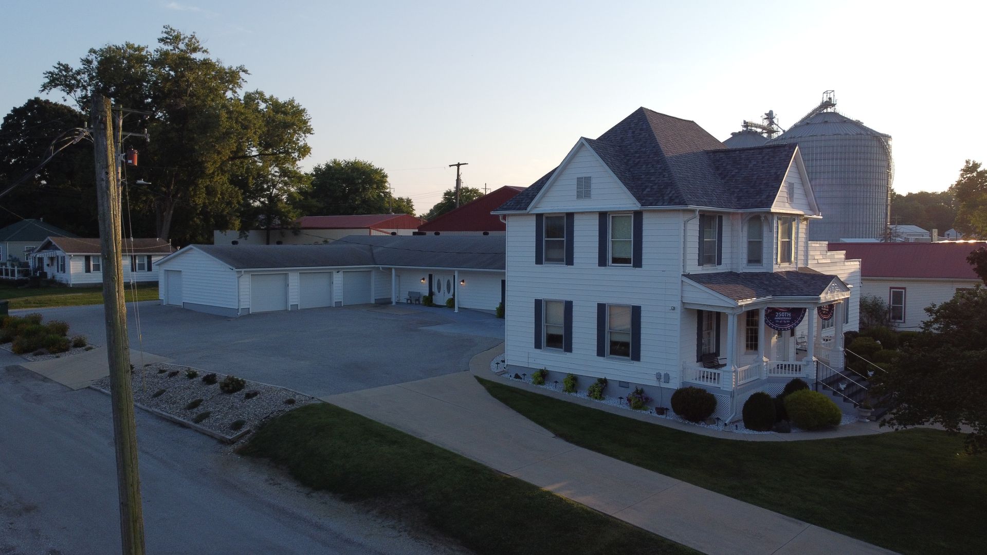 White two-story house with garage and gravel lot at dusk, seen from across the street