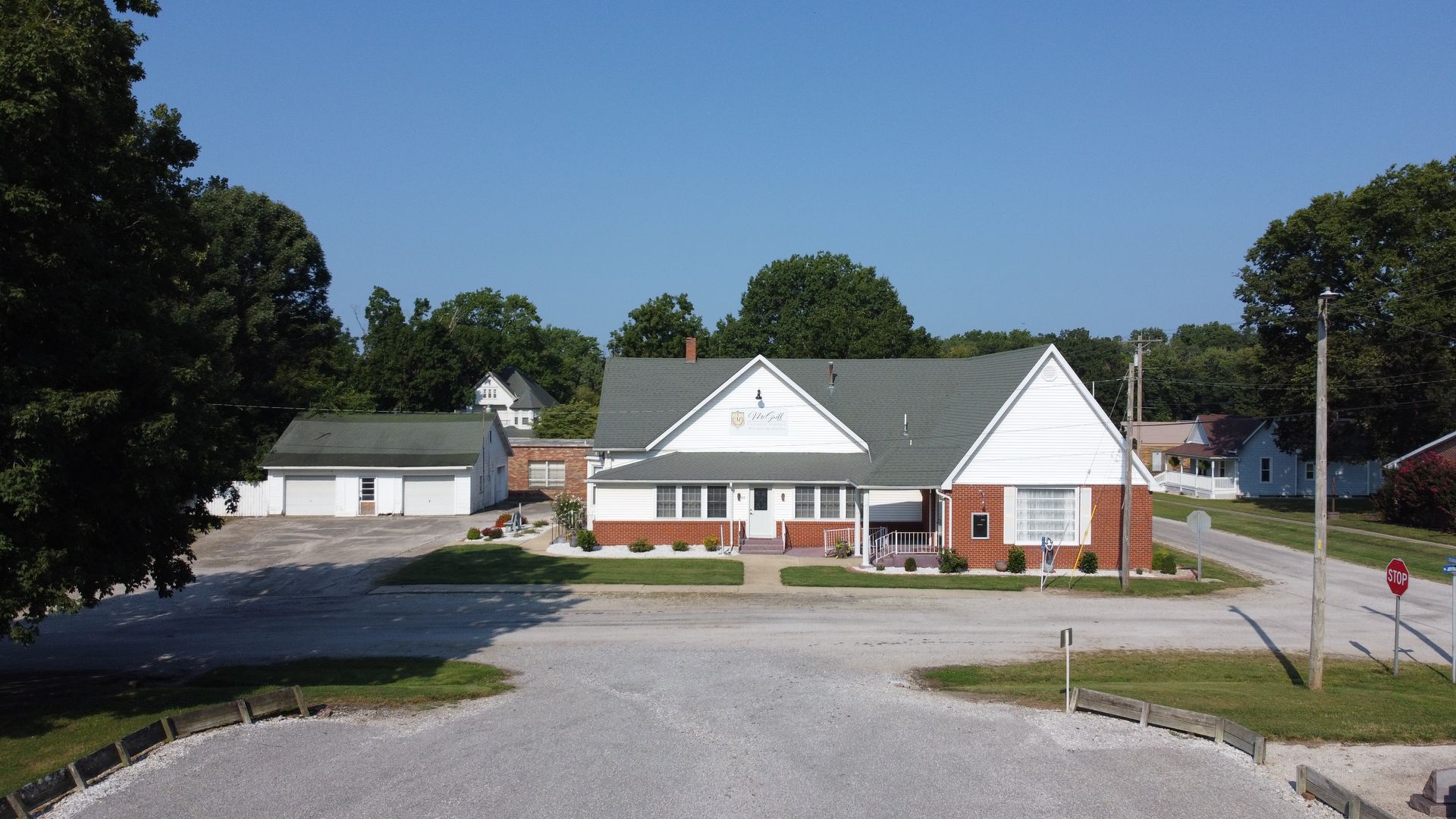 Small white and brick building beside a parking lot under a clear blue sky