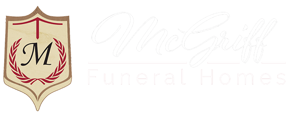Gold shield logo with red laurel wreath and black “M” over faint “McNulty Funeral Homes” text