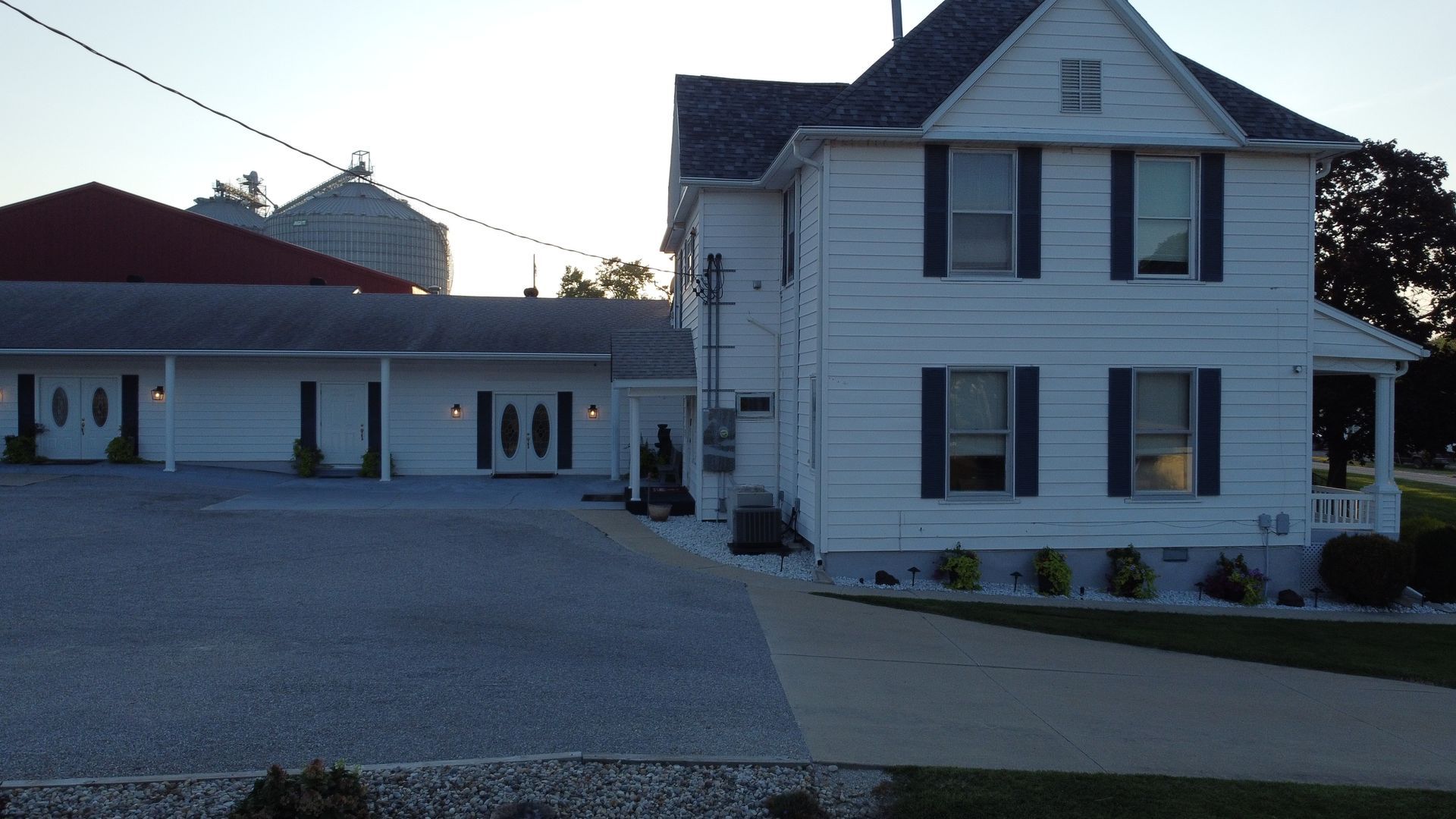 Suburban two-story house at dusk with a detached garage and lit windows.
