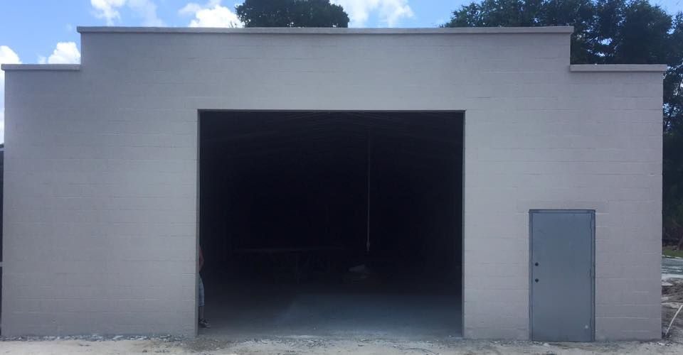 A white building with a large garage door and a small door.