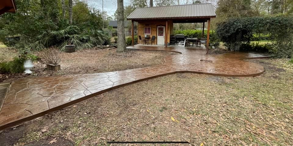 A concrete walkway leading to a house in the woods.