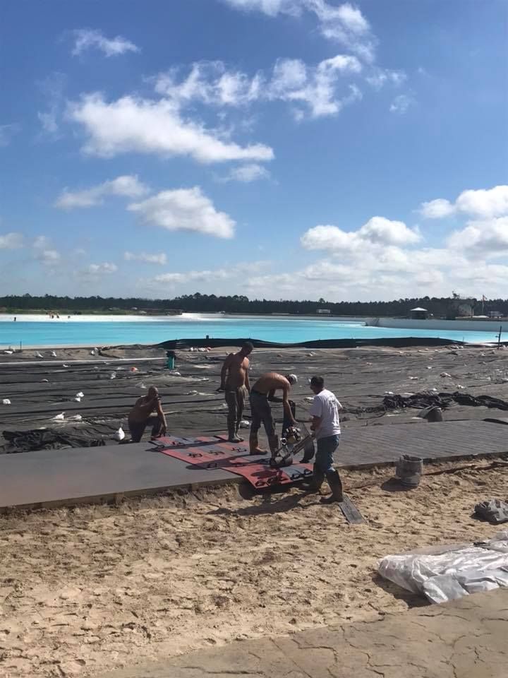 A group of people are working on a beach near a body of water