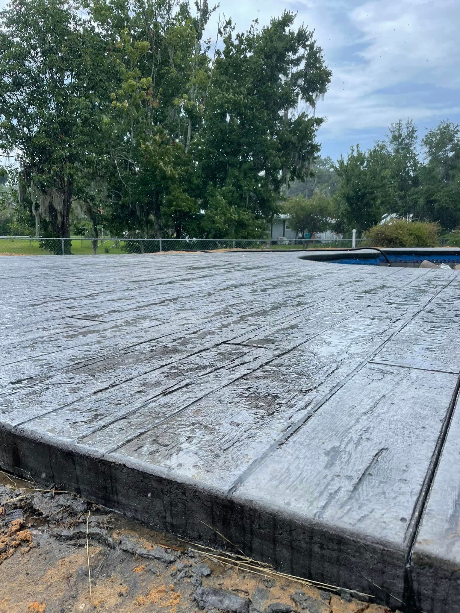 A concrete floor with a wood grain pattern and trees in the background.