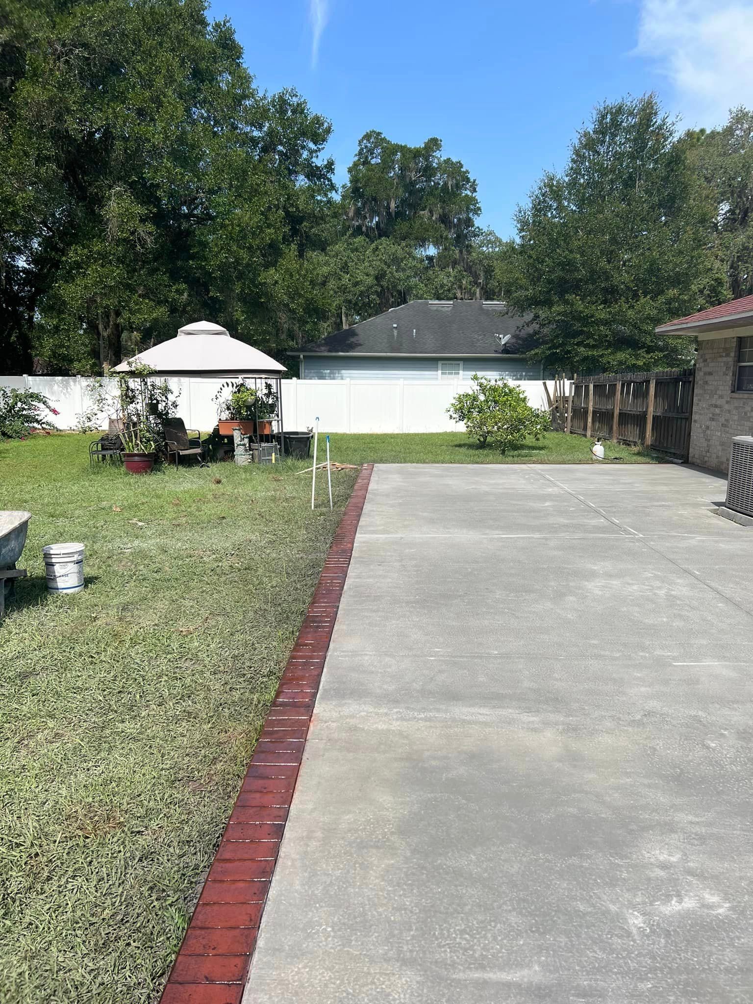 A concrete driveway leading to a house with a brick border.