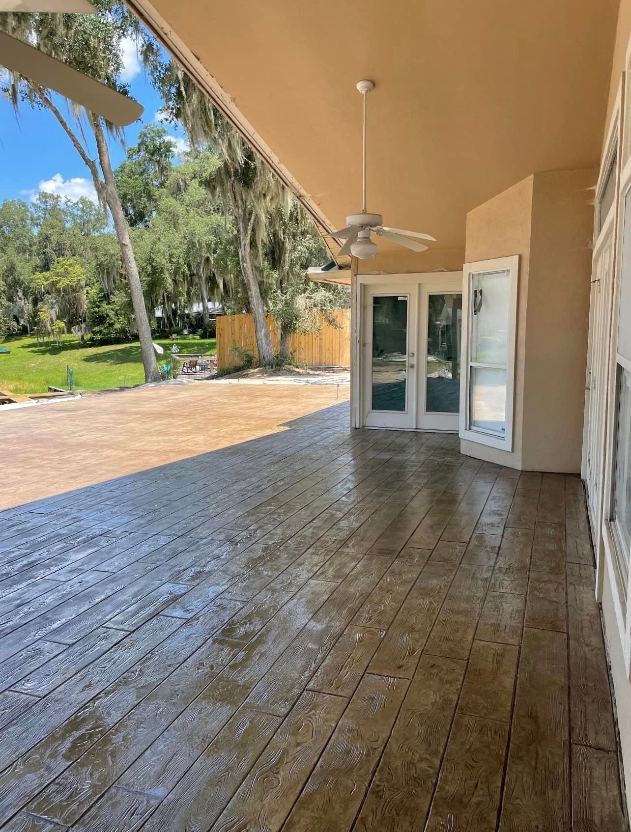 A large patio with a ceiling fan and sliding glass doors.
