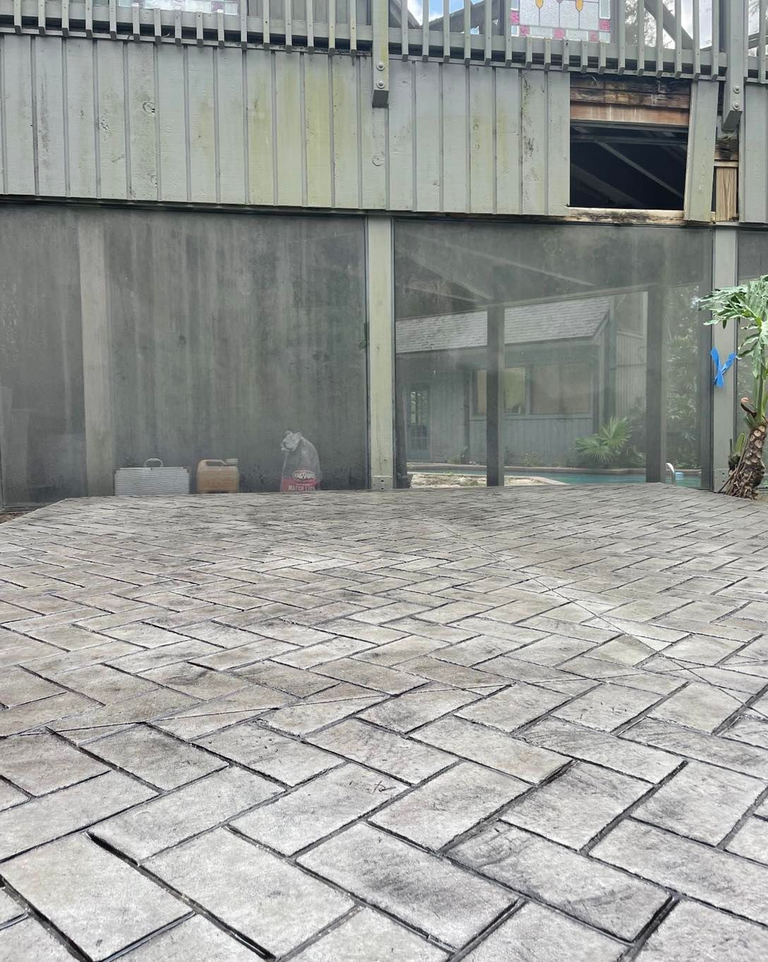 A brick driveway in front of a building with a fence in the background.
