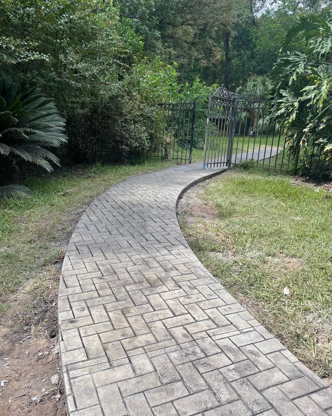 A brick walkway leading to a gate in a park.