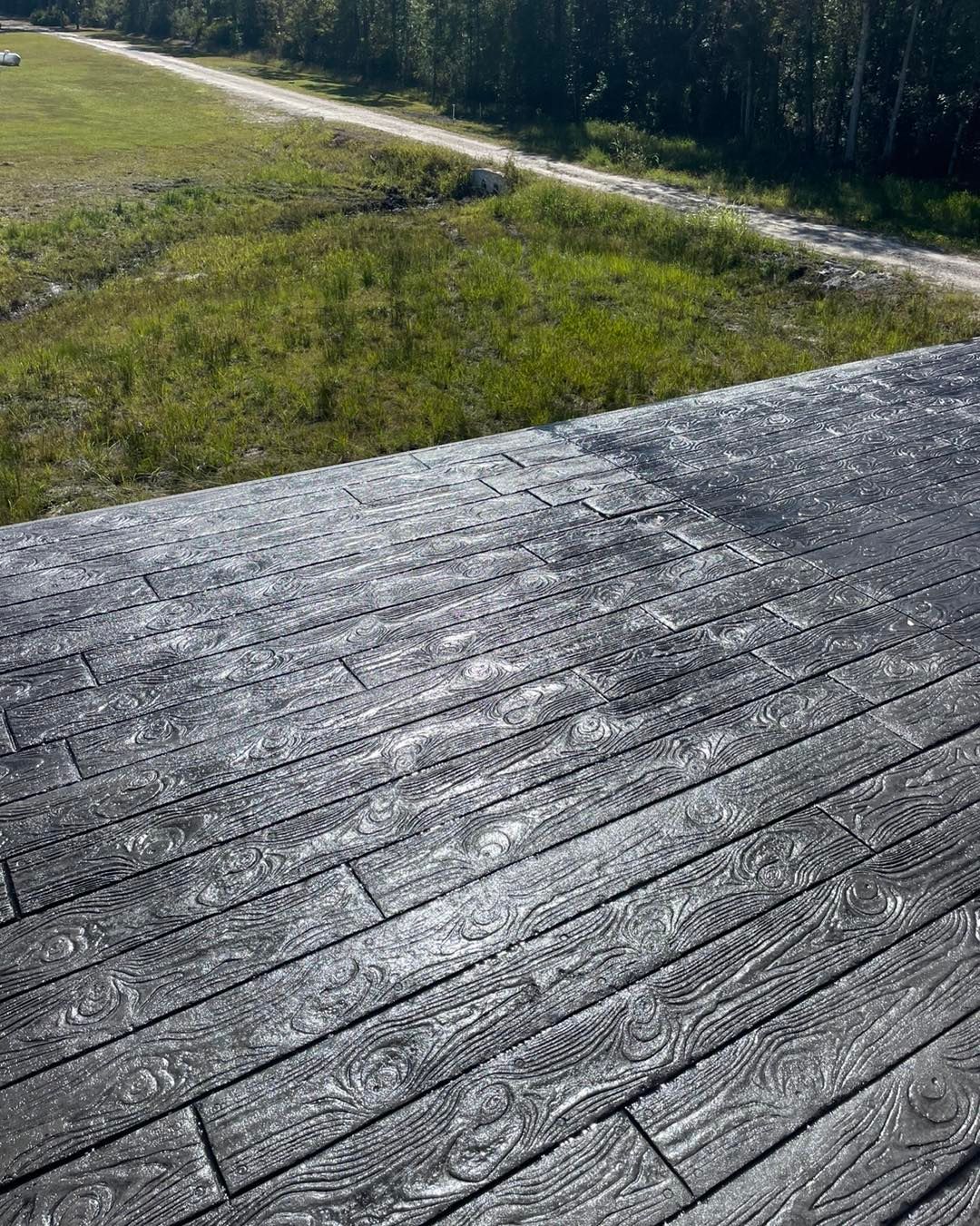 A wooden deck with a view of a field and a road.