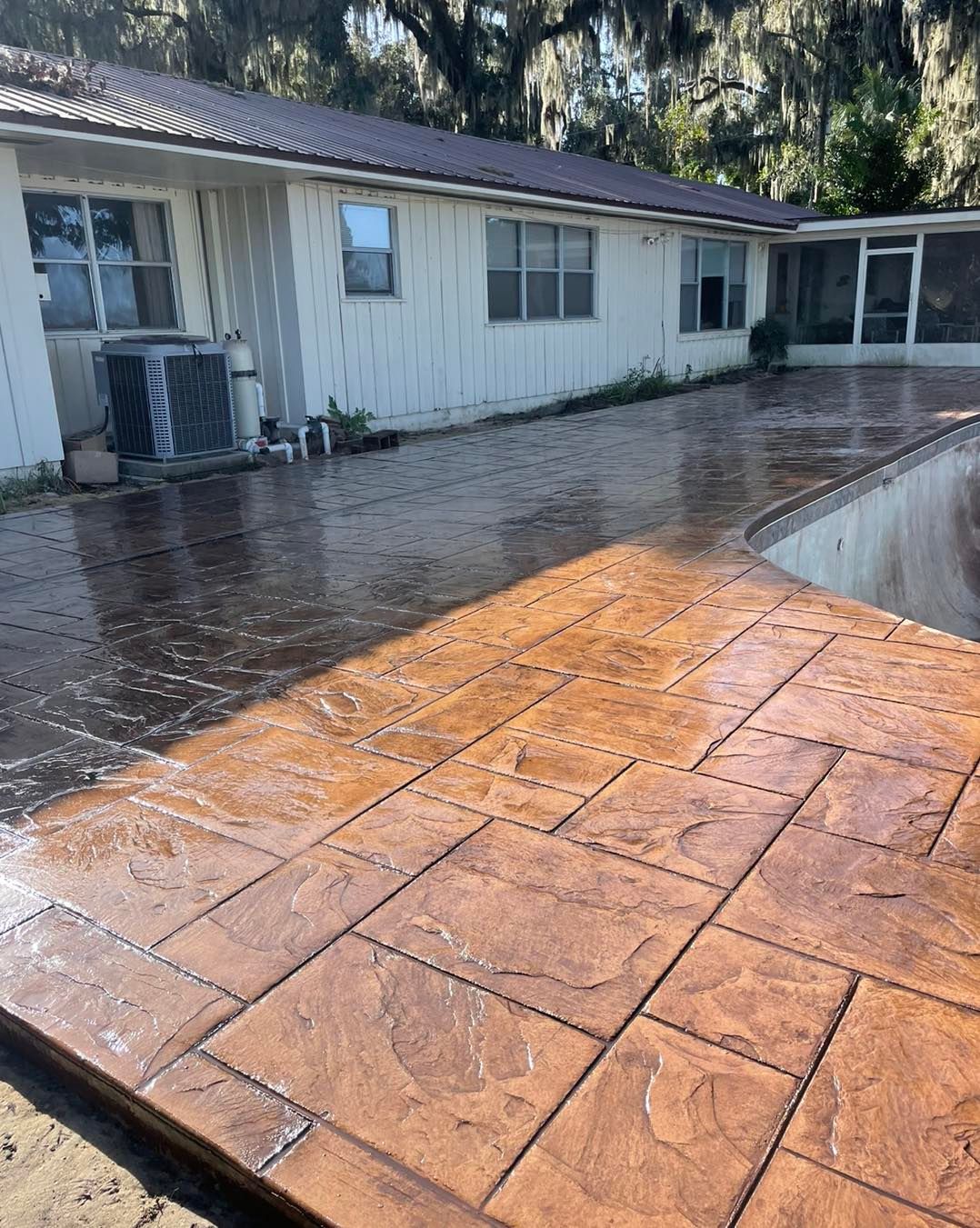 A patio with a swimming pool in the background and a house in the background.