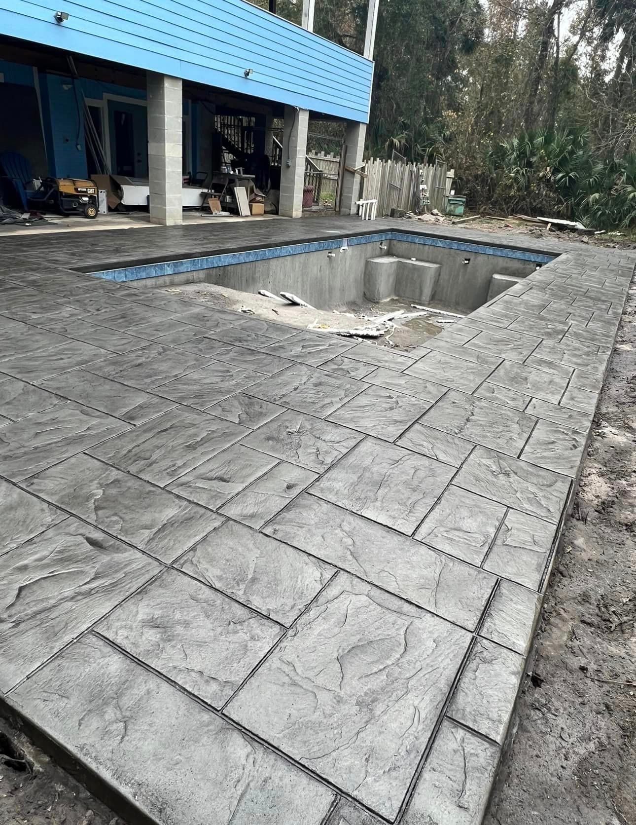 A swimming pool is being built in the backyard of a house.
