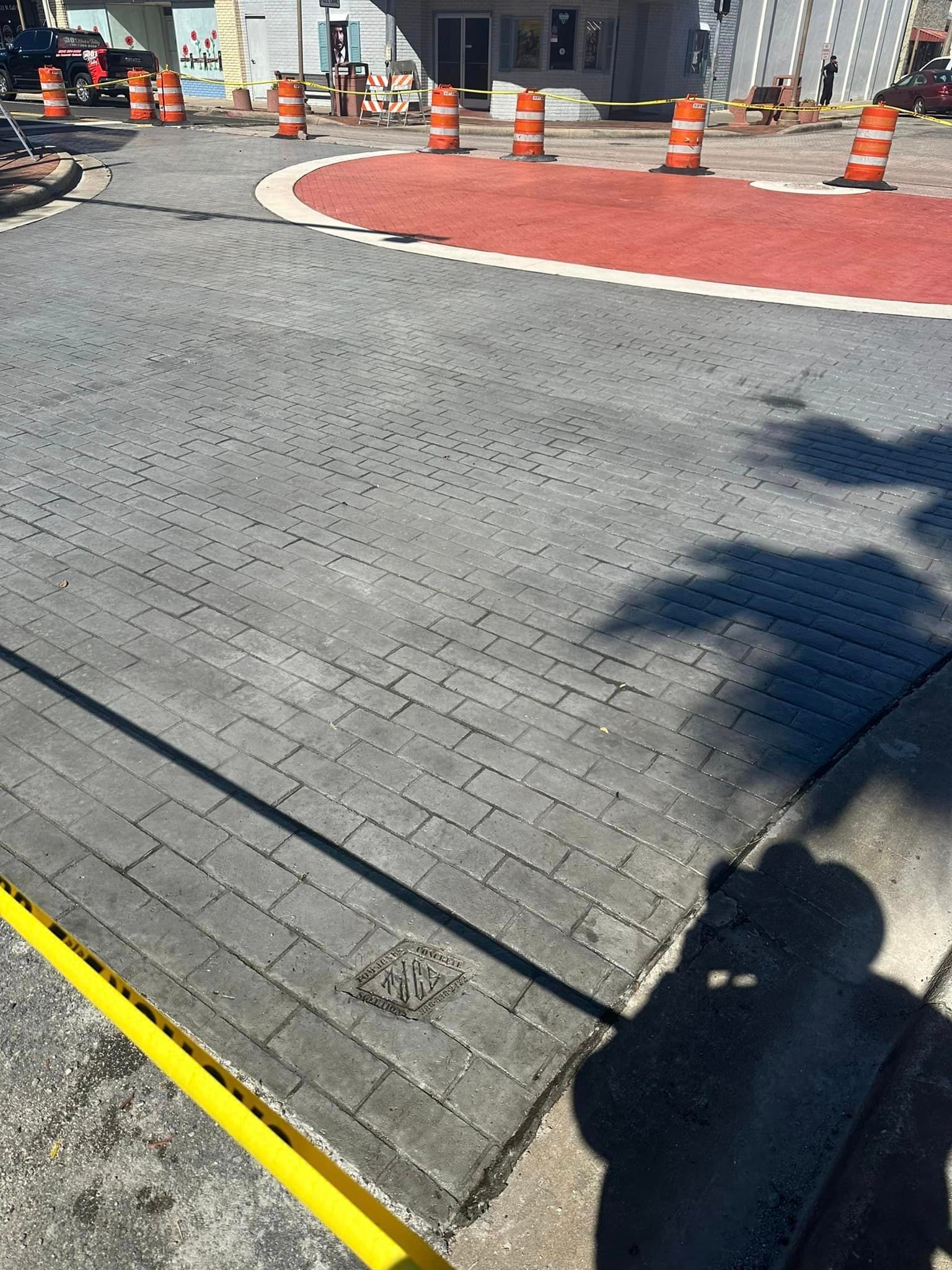A shadow of a person is cast on a brick road.