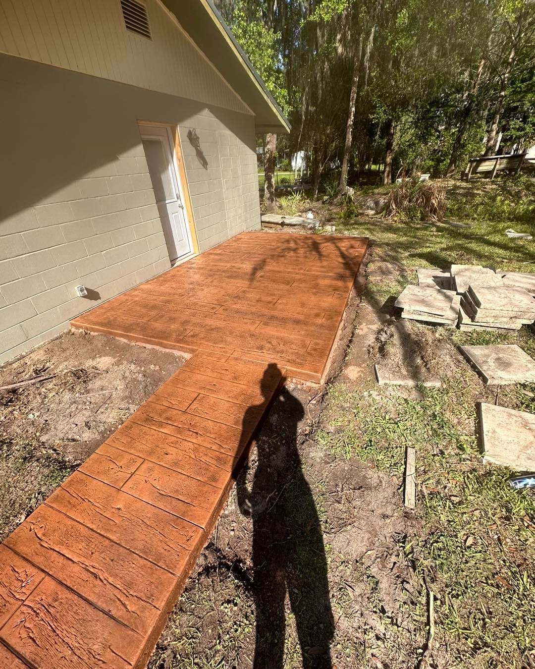 A person is standing on a concrete walkway in front of a house.