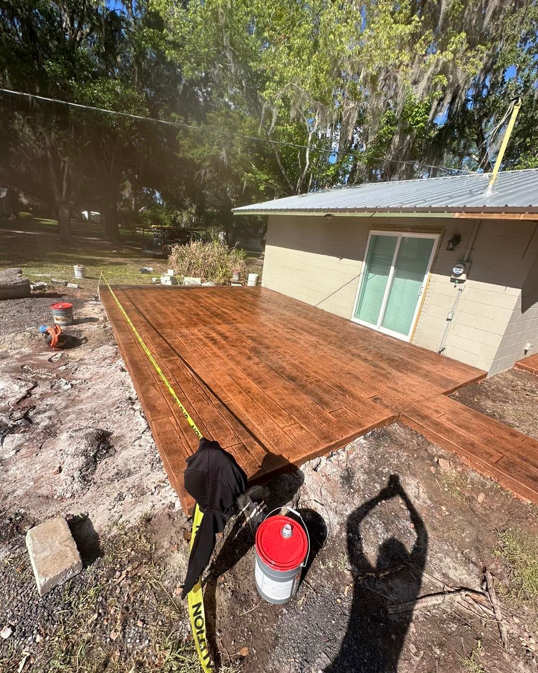 A person is measuring a wooden deck in front of a house.