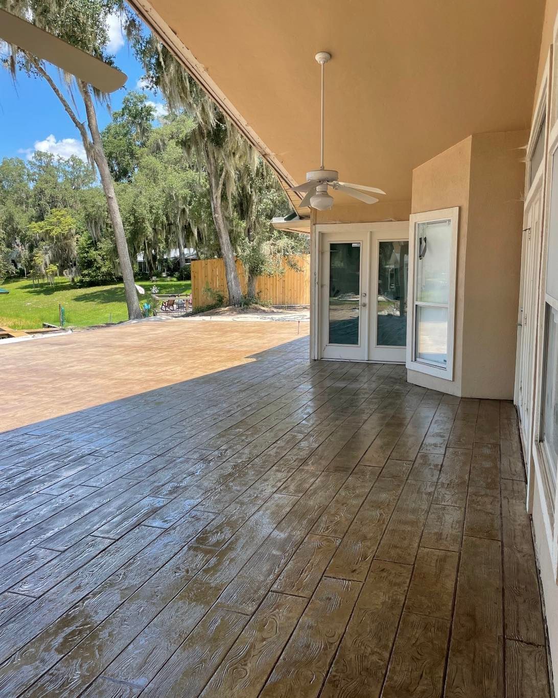 A large covered porch with a ceiling fan and sliding glass doors.
