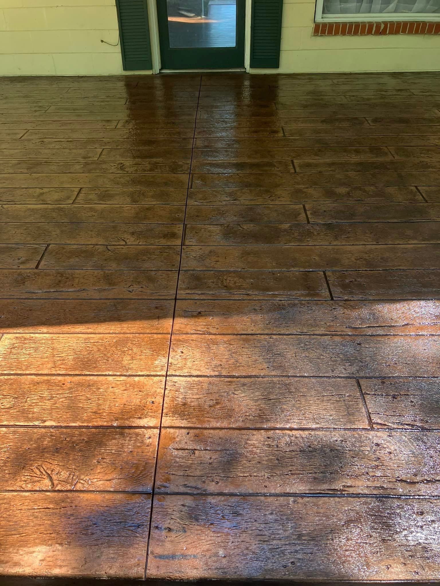 A concrete deck that looks like wood is in front of a house.
