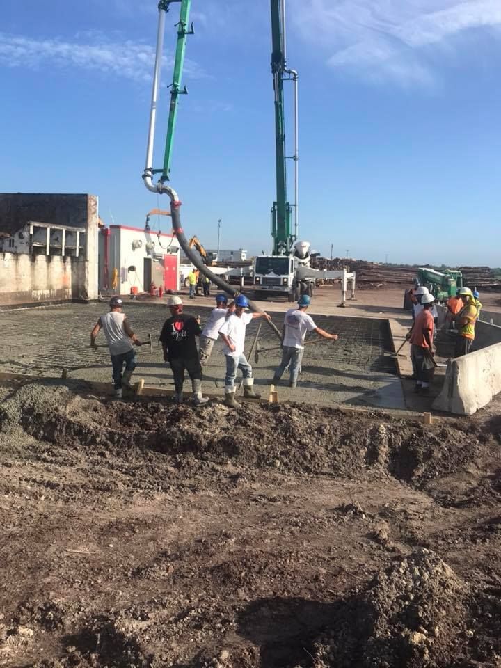 A group of construction workers are standing in a dirt field.