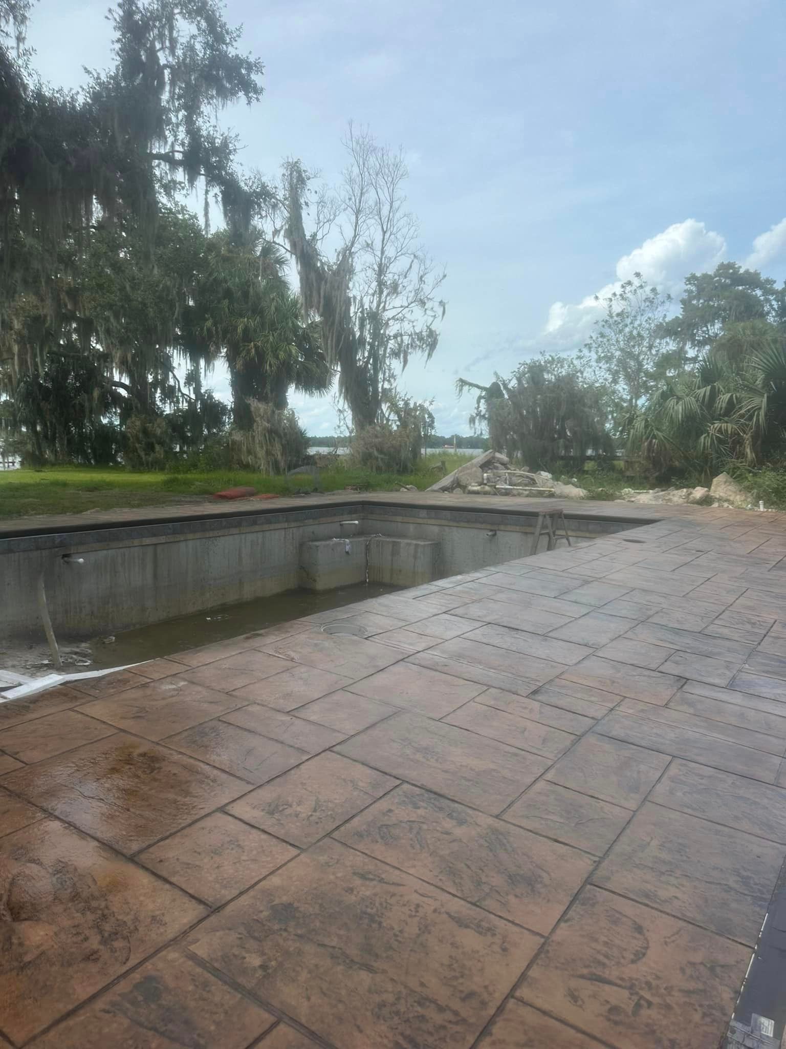 A concrete patio with a swimming pool in the background