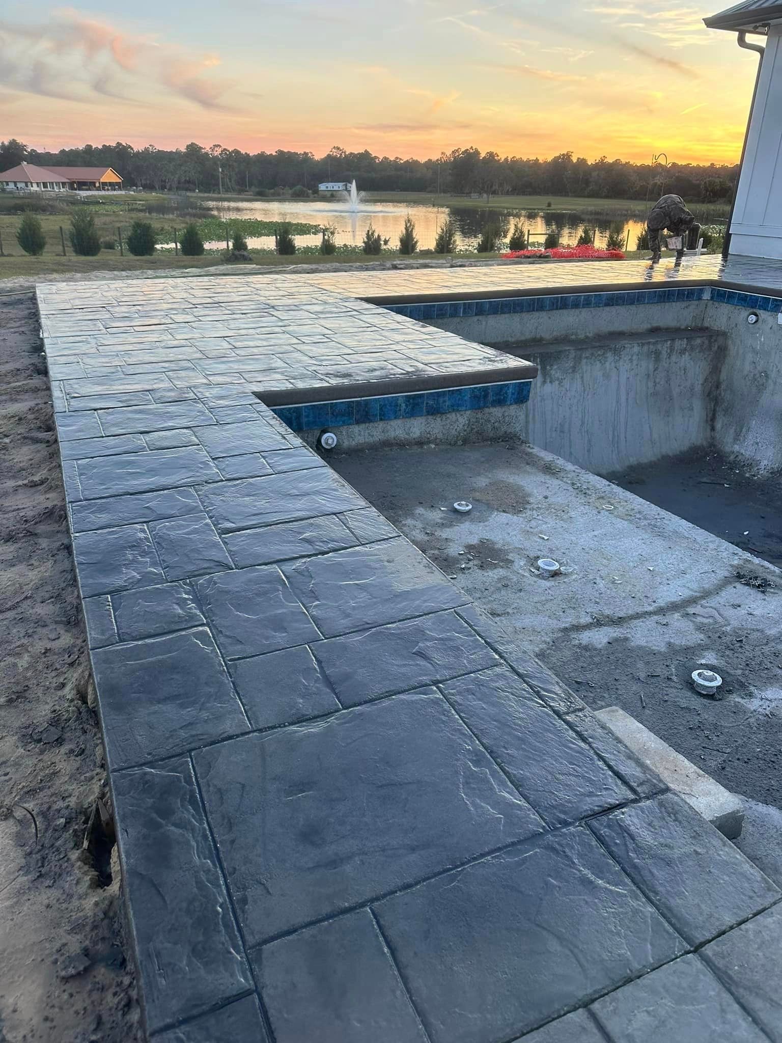 A swimming pool is being built next to a brick walkway.