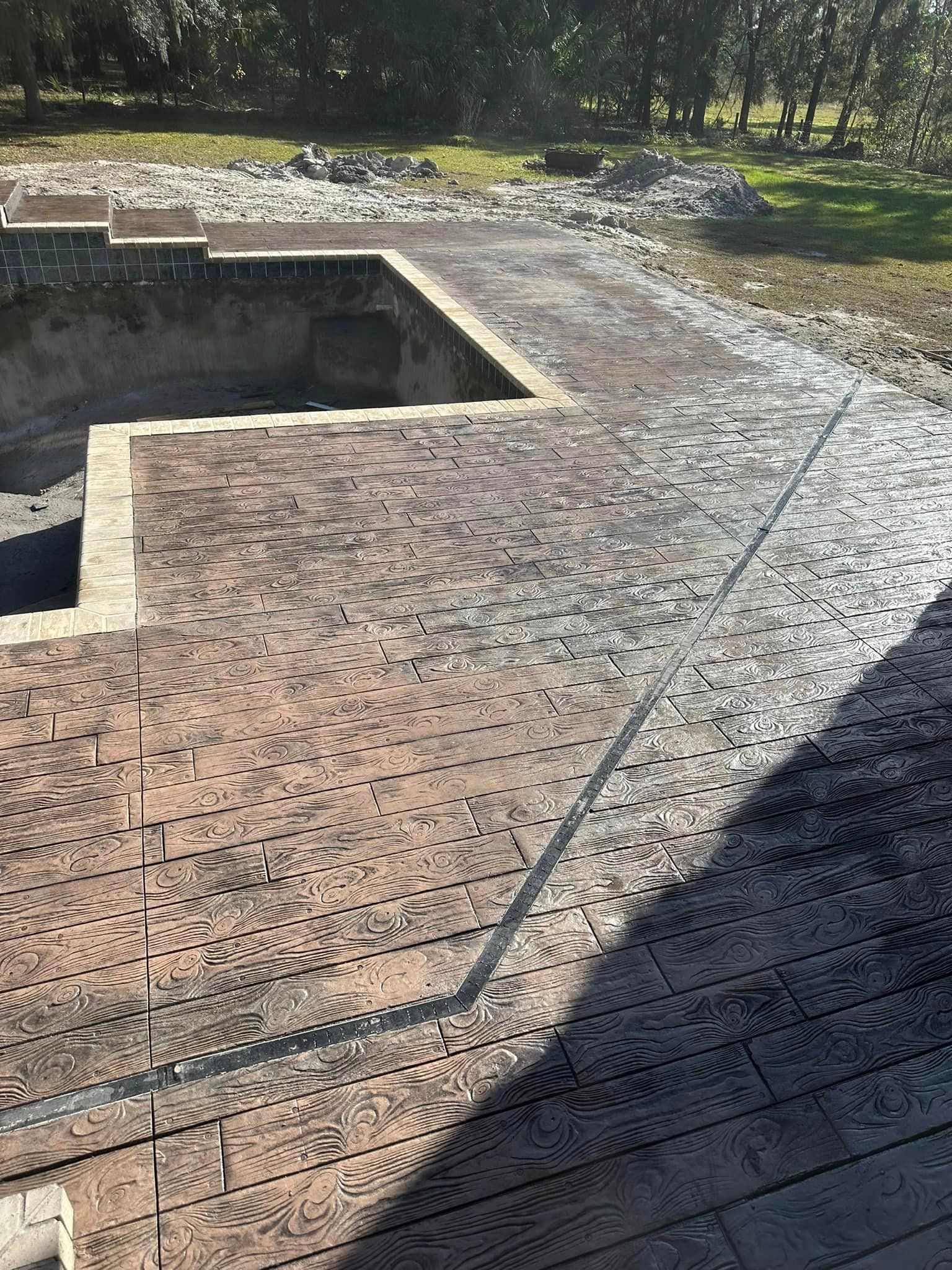 A brick walkway leading to a swimming pool in a backyard.