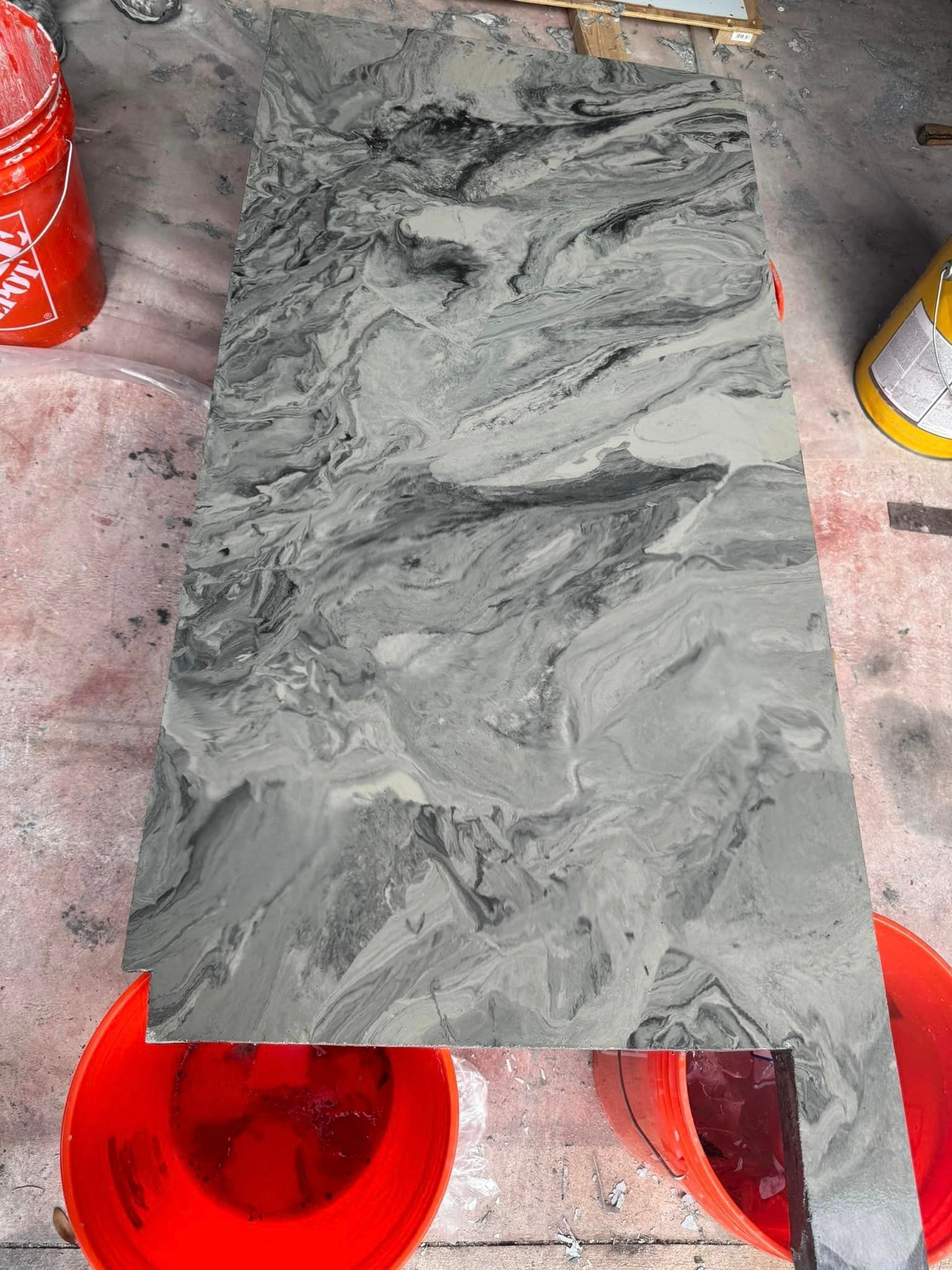 A piece of marble is sitting on top of a table next to buckets of paint.