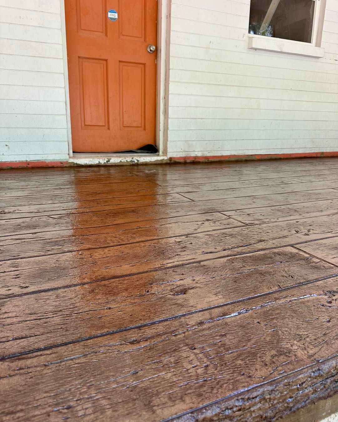 A concrete porch with an orange door in the background.
