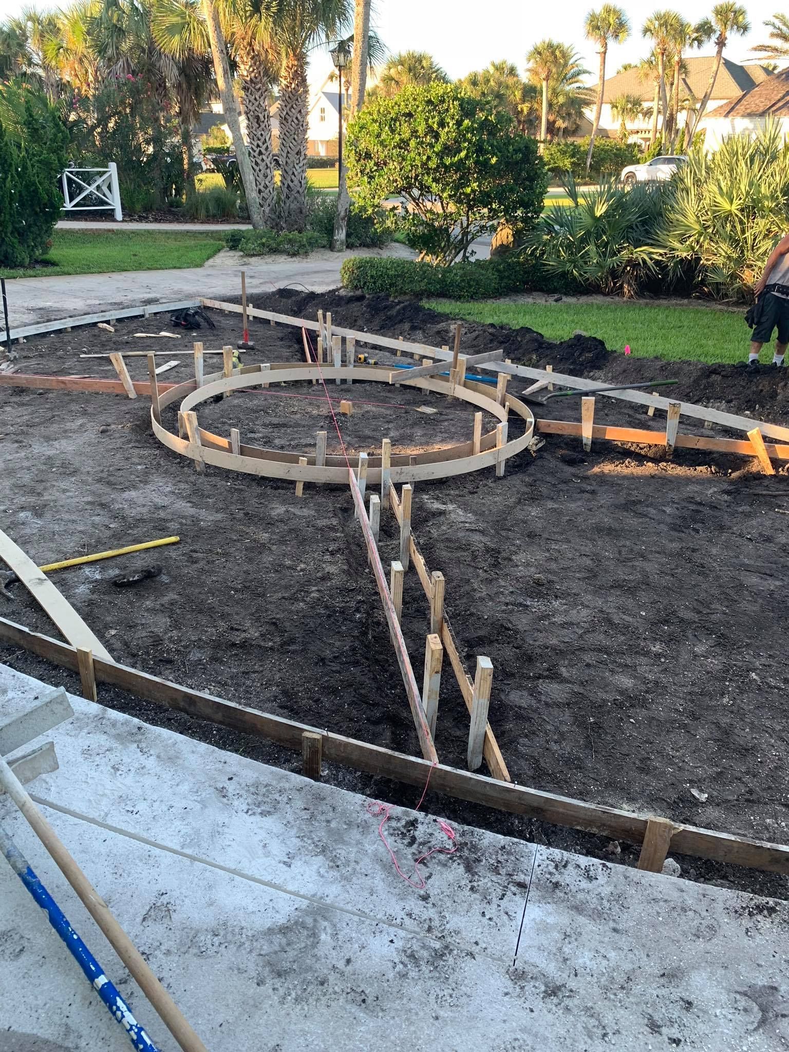 A man is working on a concrete walkway in a park.