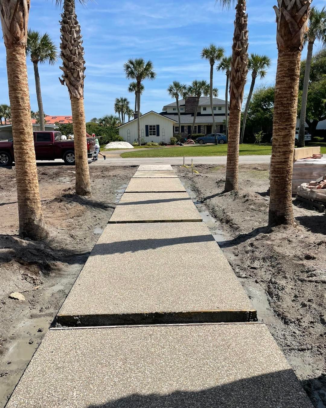 A concrete walkway with palm trees on both sides