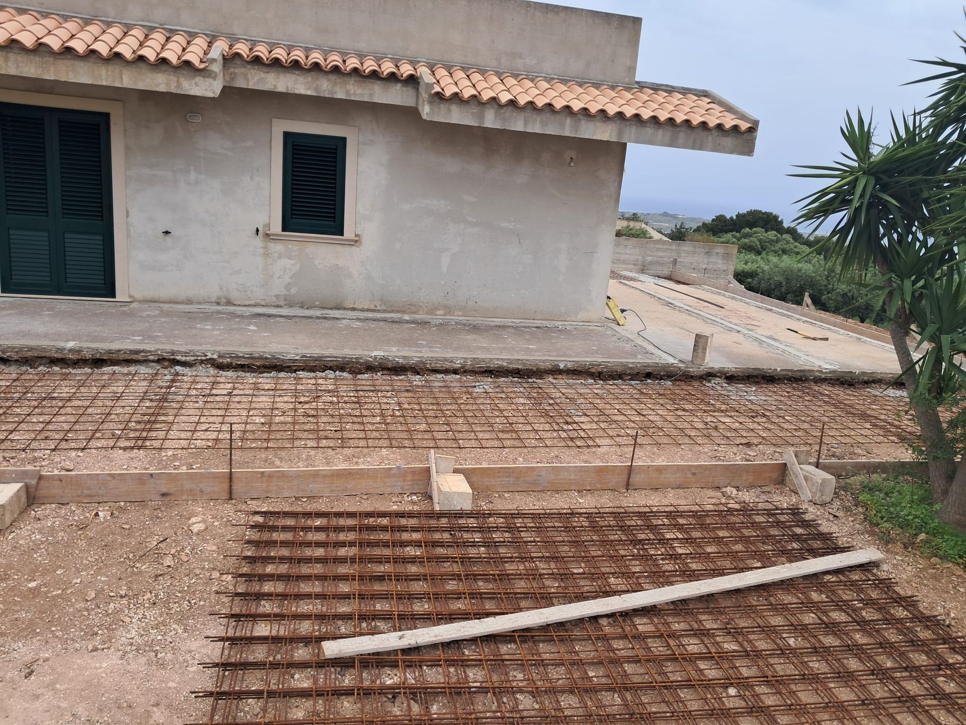 Davanti a una casa, una rampa o un vialetto in mattoni danneggiato con un'asse allentata che lo attraversa.