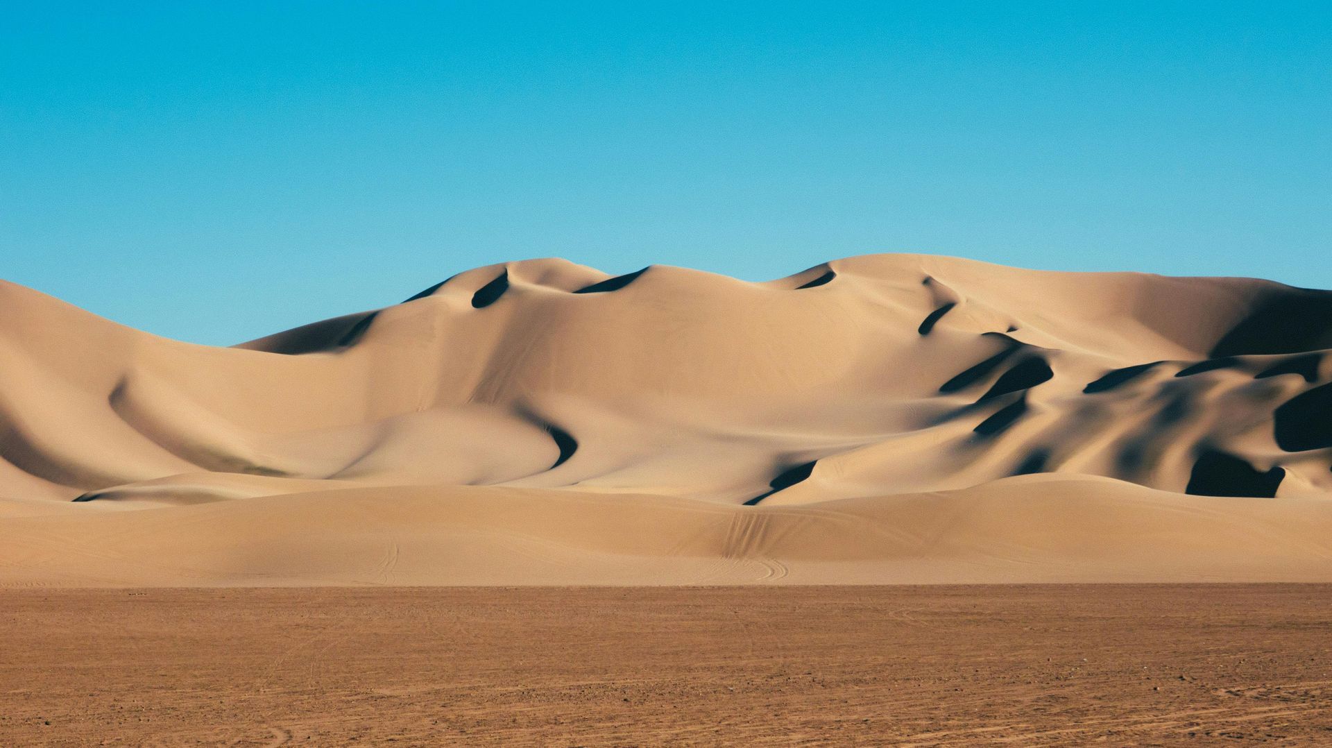 Dunas del desierto bajo un cielo azul, con texto blanco superpuesto en el centro.