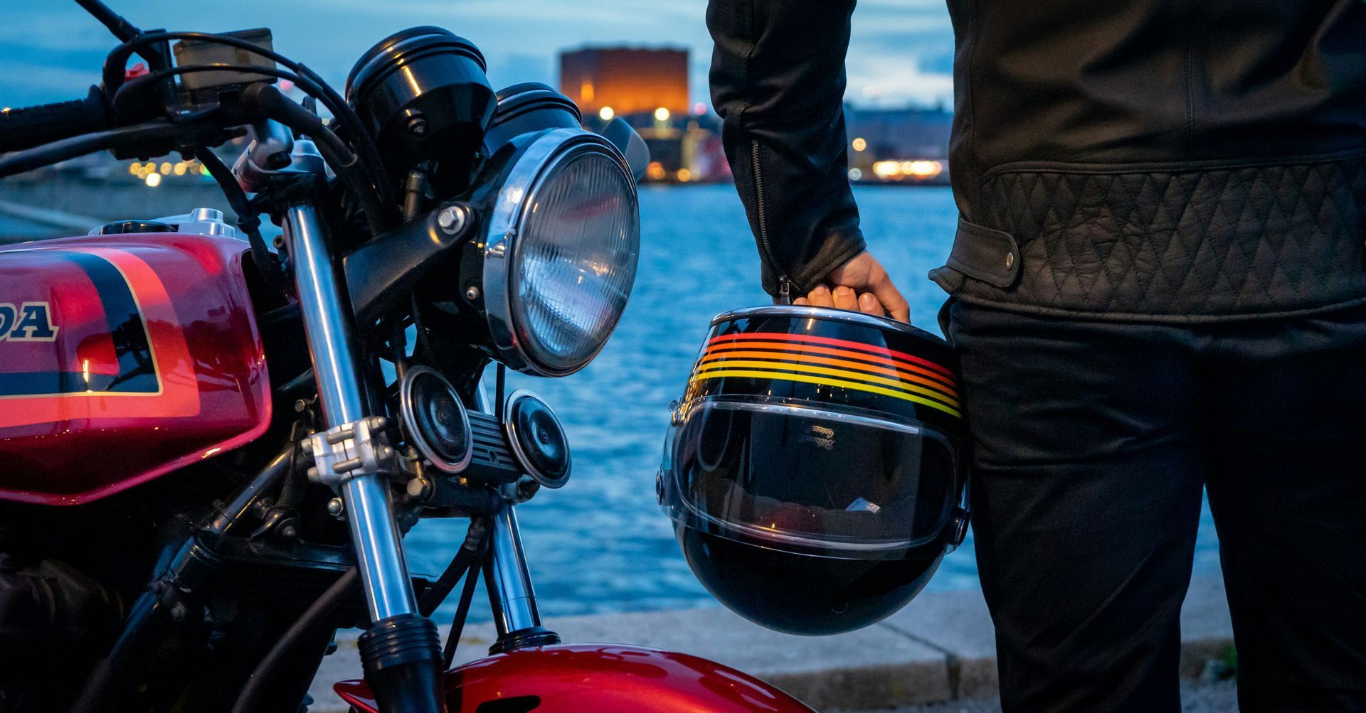 A man is holding a helmet next to a motorcycle.