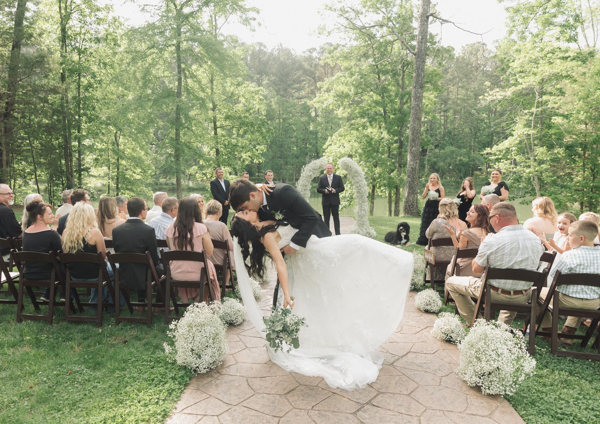 A bride and groom are kissing in front of their wedding guests.